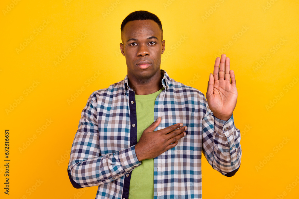 Photo of confident serious man wear plaid shirt hand touch chest shows personal patriot feeling solemn isolated on yellow color background Photo of confident serious man wear plaid shirt hand touch chest shows personal patriot feeling solemn isolated on yellow color background