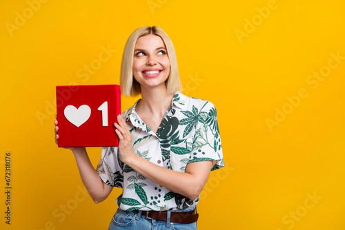 Photo of adorable dreamy woman dressed print shirt rising feedback heart looking empty space isolated yellow color background