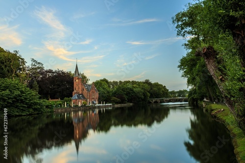 Majestic old cathedral at tranquil lake surrounded by lush greenery © Wirestock
