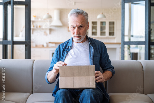Photo Mature man with frowning face receive wrong parcel, delivery post mistake