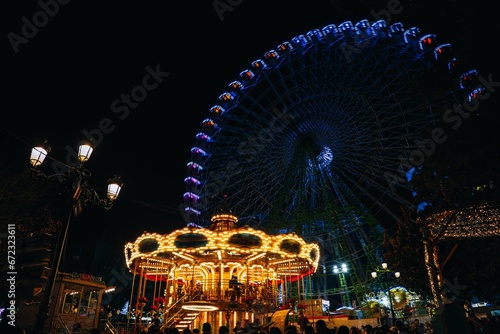 Vibrant scene of a carnival-style amusement park, illuminated by hundreds of colorful lights