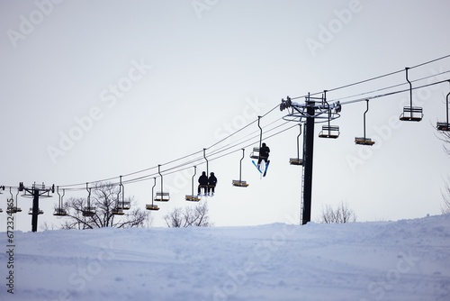 a skier rides in a lift while snow drifts below them
