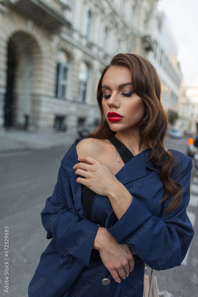 Beautiful stylish urban fashionable woman with hairstyle in a fashion blue suit walks in the city. Trendy chic elegant lady