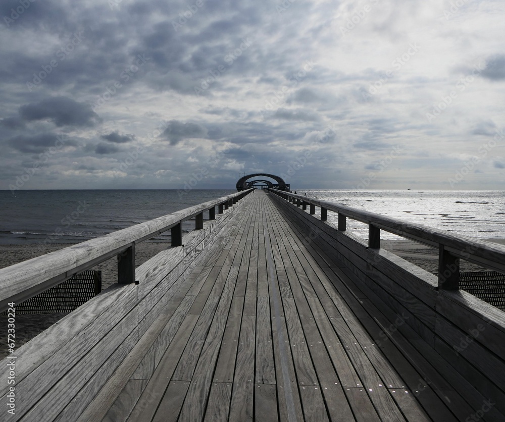 Scenic view of a wooden pier to the east sea in Kellenhusen, Holzsteg, Germany on a cloudy day