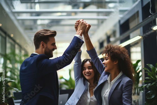 Smiling group of diverse young businesspeople celebrating success and high fiving while working together in a modern office photo
