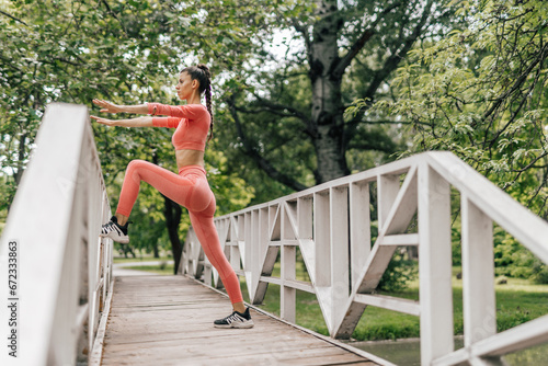 Girl stretching her legs while standing on a bridge in the park. © qunica.com