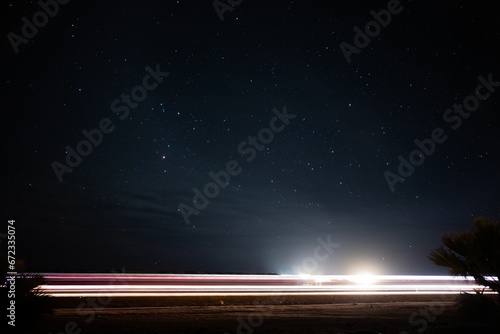 Long exposure of the light trains of a car driving down a dark road at night photo