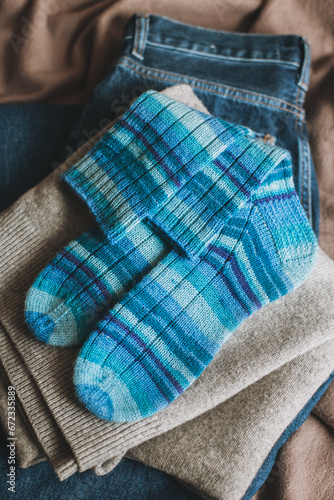 Hand knitted blue socks with sweater and jeans. Concept for handmade and hygge slow life.