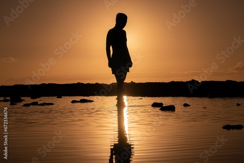 Stunning silhouette of a woman in a skirt  posing against a sunset backdrop