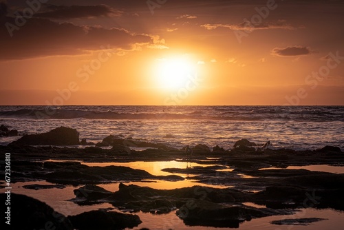 Majestic view of a beach on a sunny day, with the golden sun casting a warm light over the water