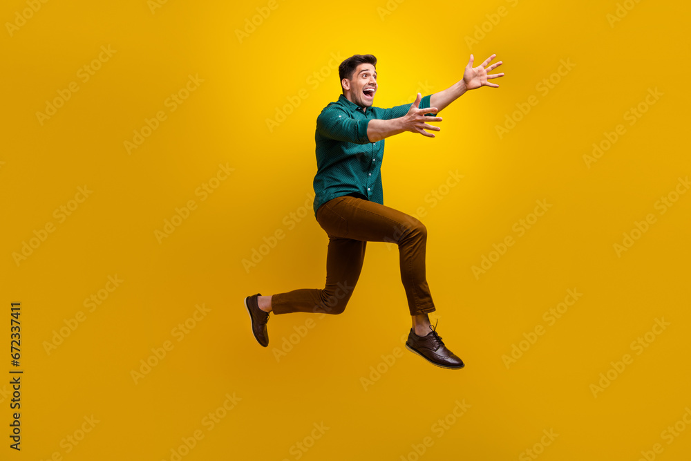 Full length profile side photo of positive cheerful glad man wear trendy clothes running empty space isolated on yellow color background