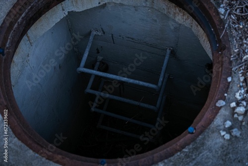 Close-up of a sewer drain featuring a ladder at the bottom with no water present