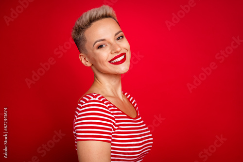 Close up side photo of cheerful cute nice lady wearing striped stylish t shirt enjoy her new clothes isolated on red color background