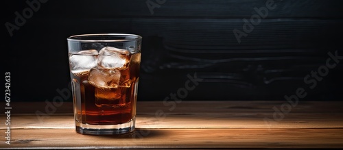 A glass of chilled water with ice alongside a cup of hot coffee with a stain on its rim placed on a wooden table Emphasis is placed on the cup and glass through selective focus