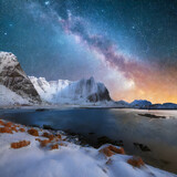 Milky Way above frozen sea coast and snow covered mountains in winter at night in Lofoten Islands, Norway