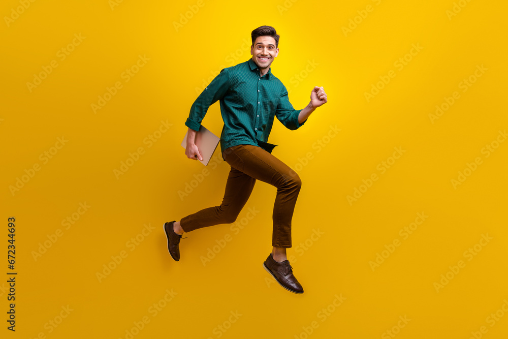 Photo of cheerful nice man wear stylish clothes run hold netbook macbook isolated on yellow color background