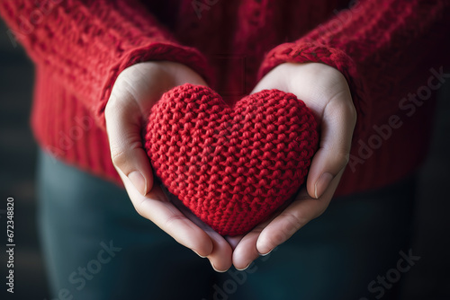closeup of hands holding knitted red heart