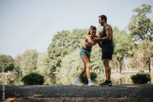 Fototapeta Naklejka Na Ścianę i Meble -  Friends Jumping Rope in a Sunny Park, a Fresh Air Workout for Young and Fit Athletes