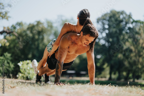 A couple trains outdoors in the park, doing push-ups as part of their daily routine. Their fit bodies inspire others with their persistent and positive results. © qunica.com