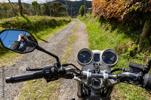 Travelling motorcyclist with his old motorbike on the road. Beautiful Colombian landscape. Travel and motorbikes.