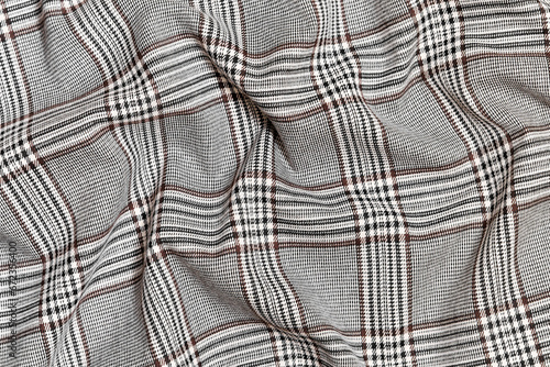 Close-up of crumpled, wrinkled texture fabric of black with brown tartan in check. Material for sewing skirts, shirts and coats. Background for your design