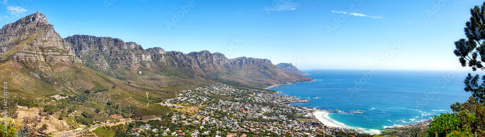 Beautiful coastal landscape with mountains surrounded an urban city in a popular tourism destination. Aerial view of Cape Town city with Mountain outcrops and the ocean on a blue sky with copy space