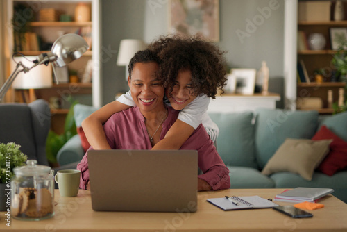 Mother and teenage son using a laptop together at home