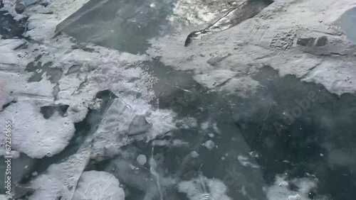 aerial. Snowy winter lake and high mountains on the horizon. Large blocks of ice on frozen water Lake Baikal. Cloudy weather photo