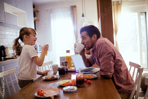 Happy little girl having breakfast with her father in the kitchen