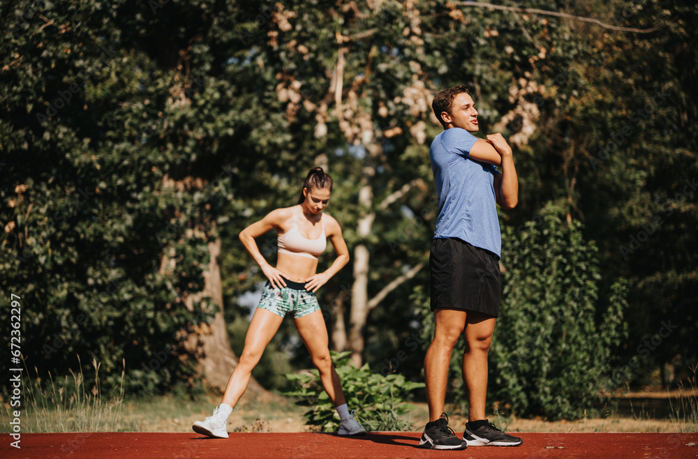 Naklejka premium Motivated couple enjoys active outdoor workout in the park. They inspire with their fit bodies, persistence, and positive mindset. Training outdoors provides fresh air and natural environment.