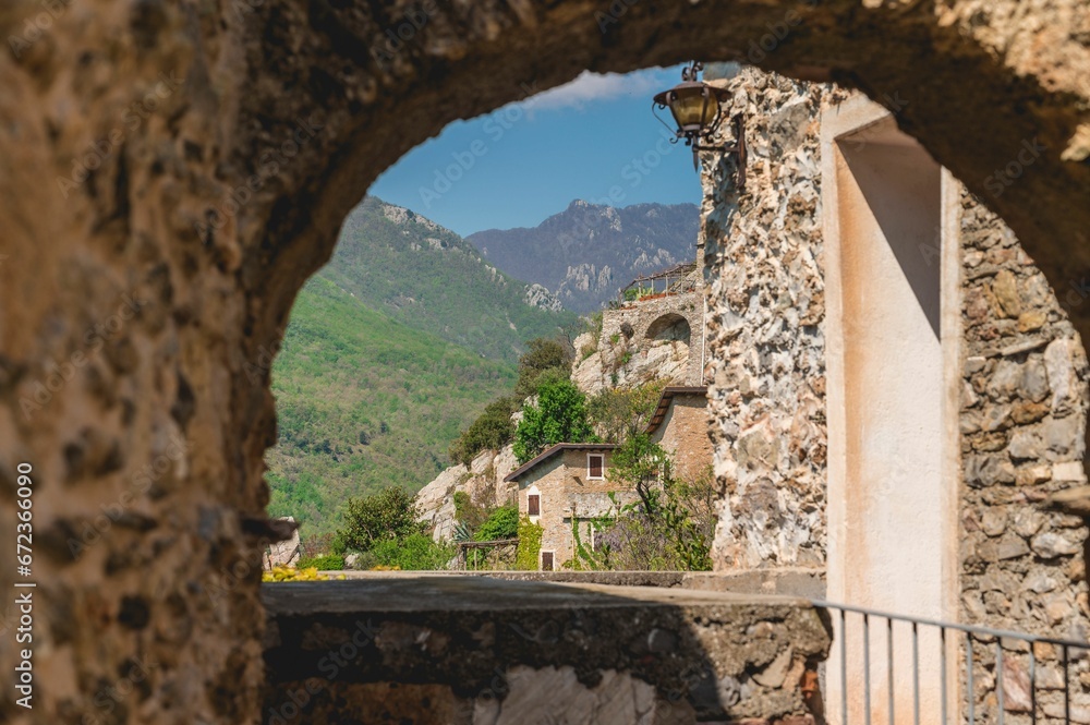 Stone archway overlooking the rolling hills and quaint villages in Castelvecchio di Rocca Barbena