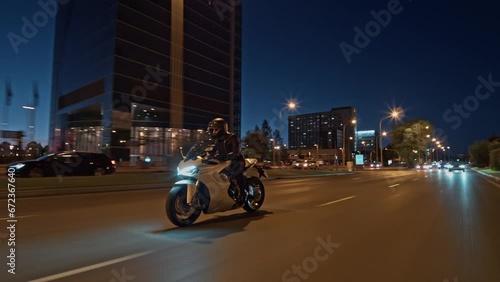 Rolling shot follow crane of man riding supersport motorcycle on the street of Madrid at night photo
