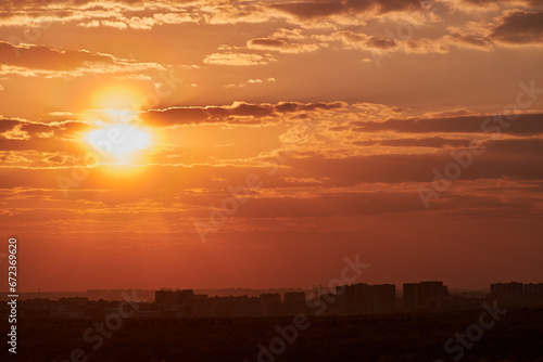 The setting sun casts a warm glow over the city, as the sky turns shades of orange and red.