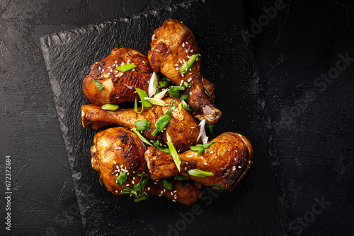 Chicken drumsticks with sesame seeds, Asian cooked chicken on a black background top view photo