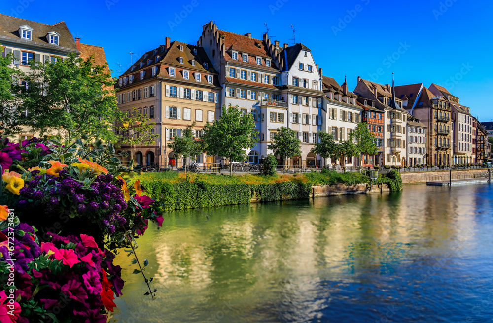 Ornate traditional half timbered houses with steep roofs above the Ill River with blooming flowers, the historic center of Strasbourg, Alsace, France