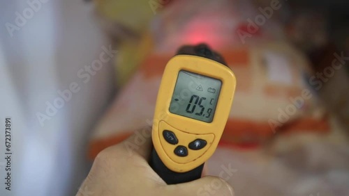 A person uses a infrared thermometer to measure the temperature of food inside a freezer  photo