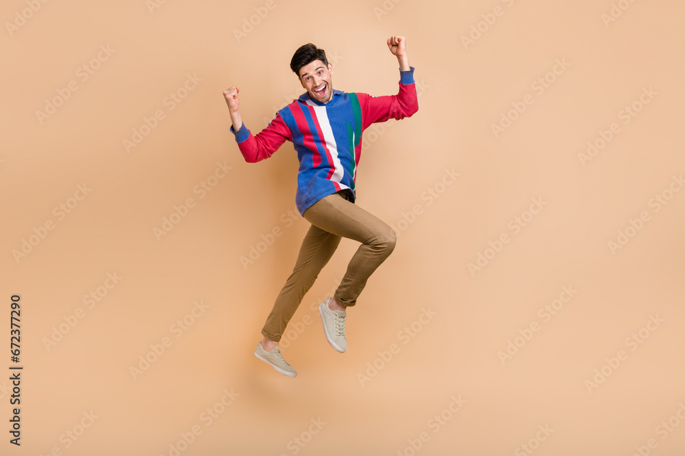 Full length size photo of funny ambitious man jumping raise fists celebrate his promotion new job offer isolated on beige color background