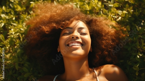 Smiling young black woman lying on the grass © Ricardo Costa