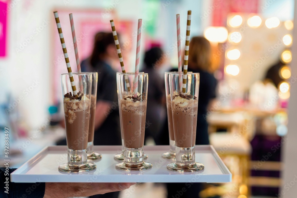 Closeup of chocolate milkshakes with whipped cream and straws in a glass