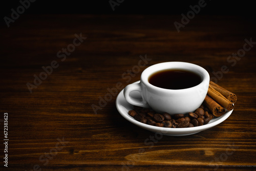 A cup of aromatic black coffee. Morning espresso or Americano coffee for breakfast in a beautiful cup. Cinnamon sticks. Wooden background.