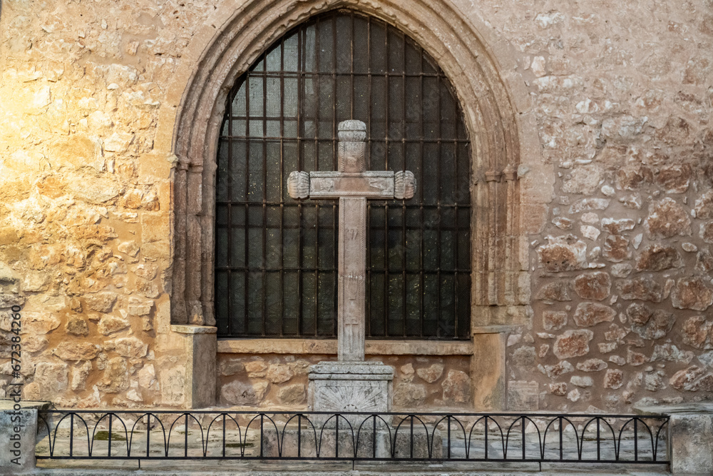Fototapeta premium Medieval stone cross infront of the window of a church.