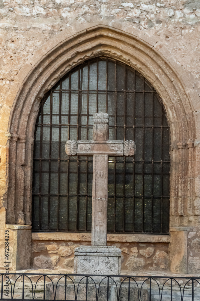 Fototapeta premium Medieval stone cross infront of the window of a church.