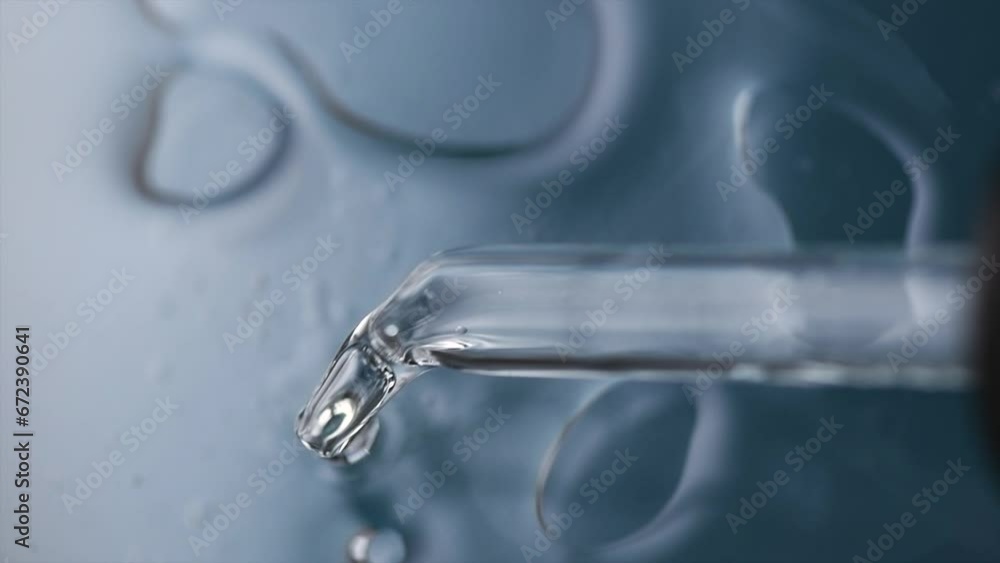 Cosmetic dropper with serum, essential oil, beauty skin care cosmetics dripping, on blue background. Macro shot. Serum, peptides, beauty and health care products. Glass pipette with liquid. Top view. Cosmetic dropper with serum, essential oil, beauty skin care cosmetics dripping, on blue background. Macro shot. Serum, peptides, beauty and health care products. Glass pipette with liquid. Top view.
