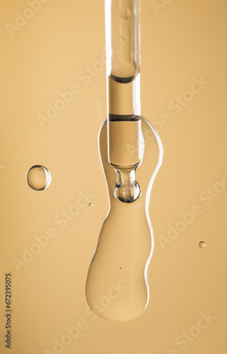 Cosmetic dropper with serum, beauty cosmetics dripping, on beige background. Macro shot. Serum, peptides, beauty and health care products. Glass pipette with liquid, close up. Top view. Skin care 