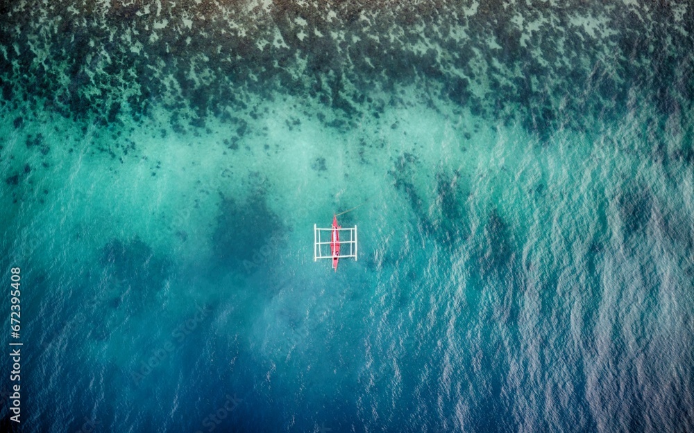 Aerial view of white and red bankga boat in blue and turquoise sea by the algal shore - obrazy, fototapety, plakaty 