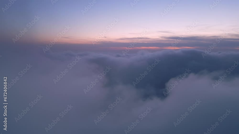A drone flies over fluffy clouds at sunset. The drone flies through the clouds, creating a sense of wonder and awe