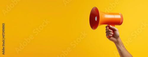 Hand holds megaphone on yellow background with copy space. Banner with loudspeaker for advertising ads