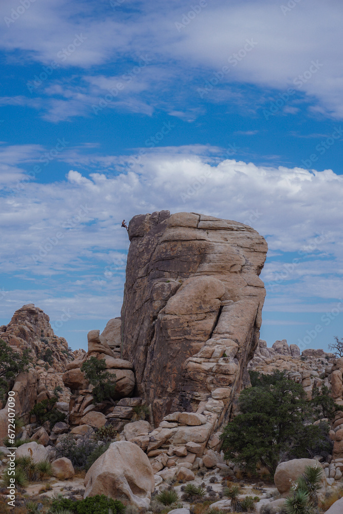 Man climbing on top of a huge rock