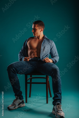 Strong, fit, male gym lover showing his beautiful torso while sitting on a chair