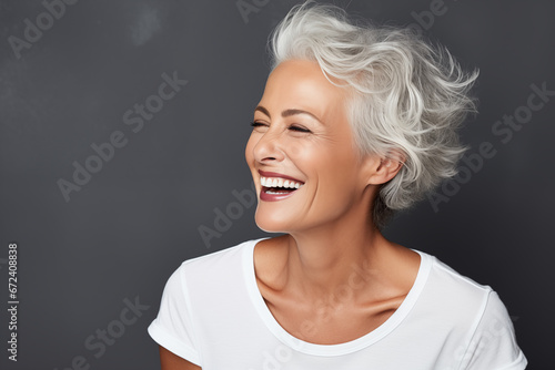 Beautiful gorgeous 50s mid age beautiful elderly senior model woman with grey hair laughing and smiling. Mature old lady close up portrait. Healthy face skin care beauty, skincare cosmetics, dental. 